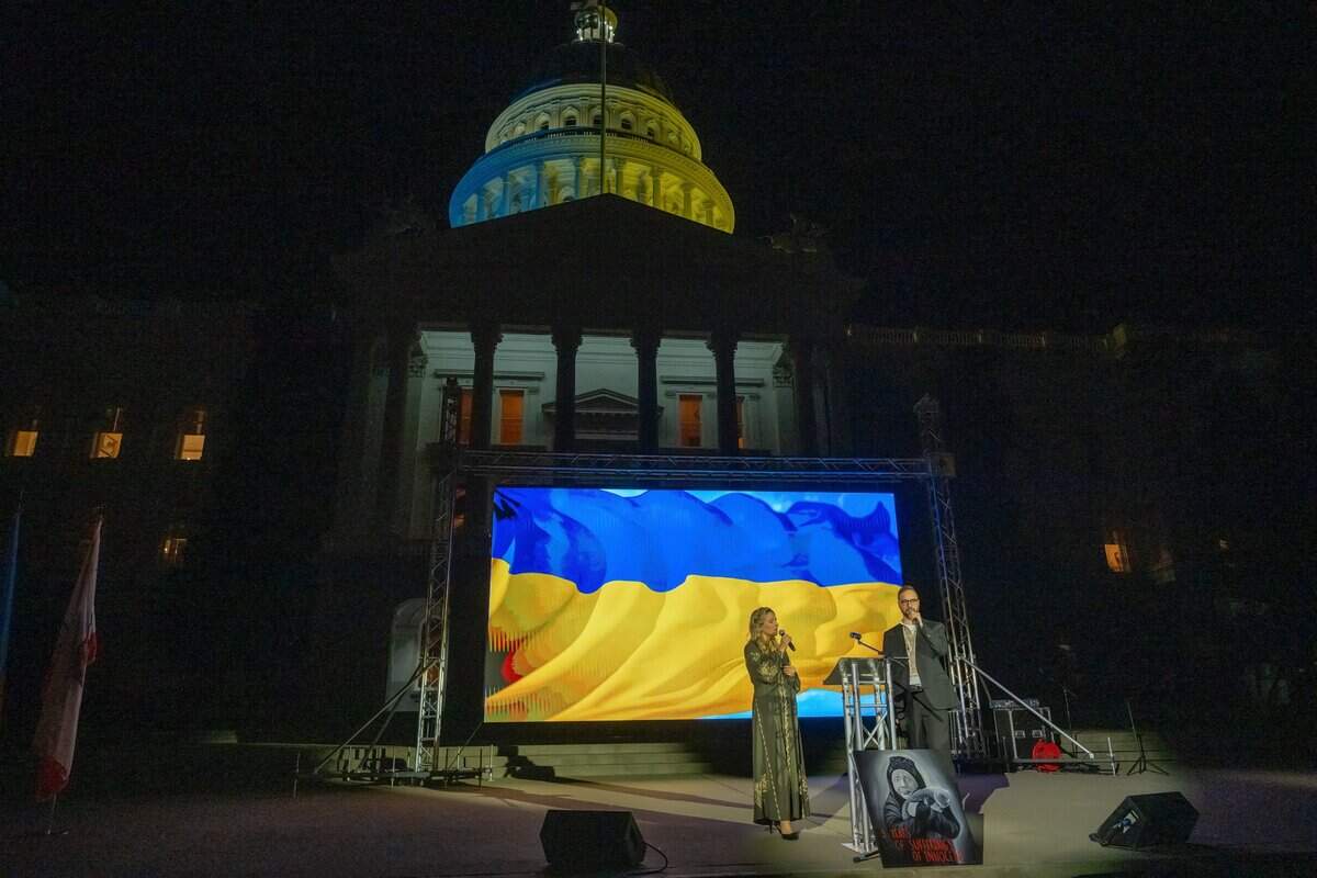 The dome of the California Capitol is lit with yellow and blue light as Svitlana Iotko, left, and Yuliy Tsymbal, right, host an event on Monday, Feb. 24, 2025, marking the third anniversary of the Russian invasion of Ukraine.