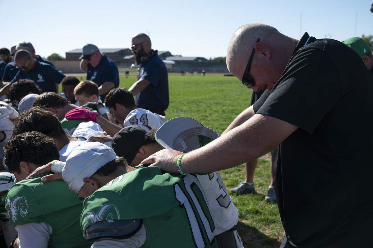 Dixon coach Wes Besseghini prays with members of the Dixon and Casa Roble high school football teams after they played in Dixon on Saturday. The game follows the death of one of Dixon’s junior varsity football players.