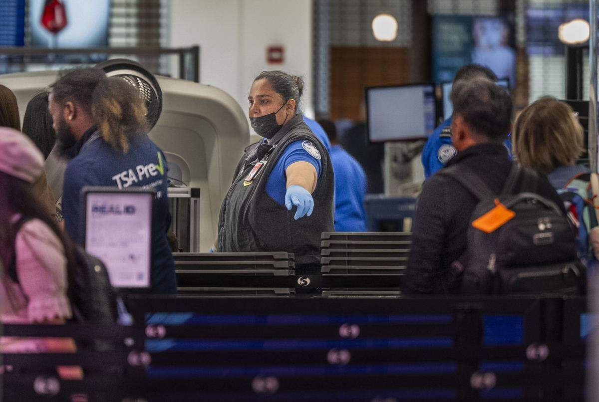 A Transportation Security Administration worker directs passengers at Terminal A in the Sacramento International Airport after a news conference on Friday about the federal government shutdown. TSA workers have been working without pay.