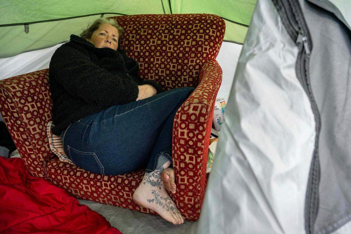 Ginger Gibbons, 56, curls up in her Sacramento tent on Thursday. She recently was arrested by city police, and when she got out of jail she said all her belongings were gone. “They call it camping, but we are not campers – we are survivalists,” she said. “Camping is when you go out and have a fun trip – this isn’t camping, this is miserable.”