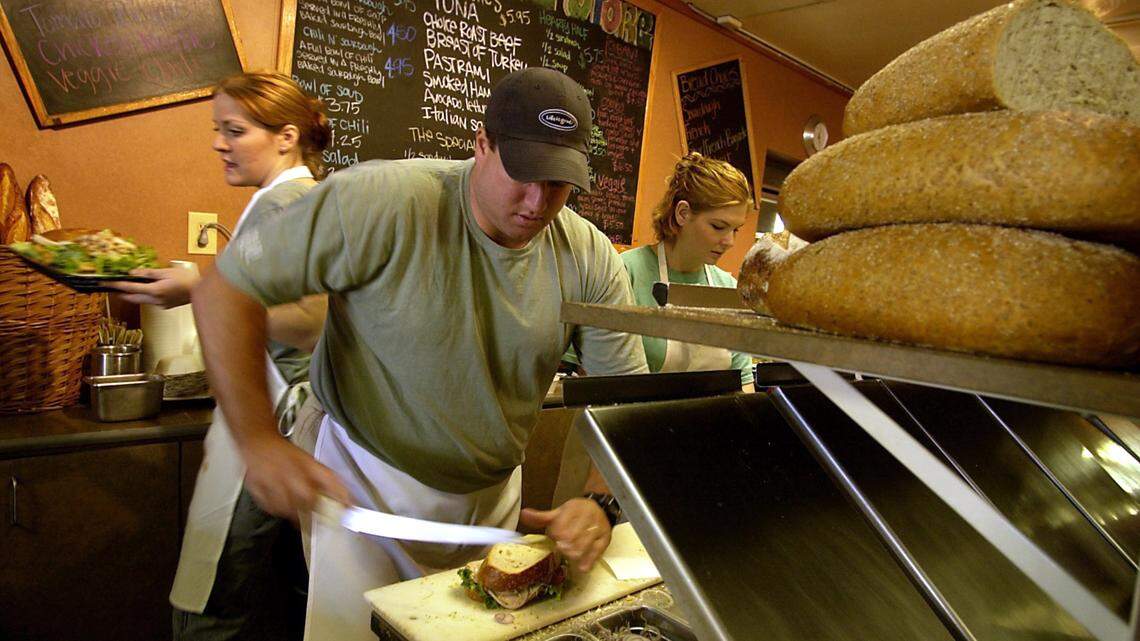 Andy Smith, owner of The Bread Store in Sacramento works to prepare a sandwich for the lunch crowd while Amanda Swift, 20, squeezes behind him to serve a sandwich and Ashley Patser, 19, right, helps prepare more orders in November 2003.