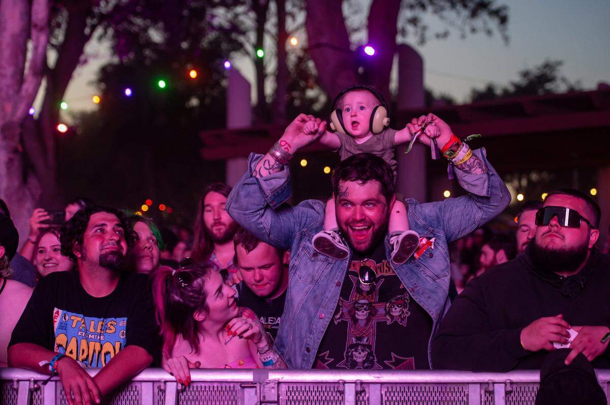 Krisma Pickering, center, of Eugene, Ore., looks up at her 8-month-old son Halen as he sits on Travis Hill’s shoulders while Bring Me the Horizon performs on the Jack Daniel’s Stage on the fourth day at the Aftershock rock festival Sunday, Oct. 9, 2022, at Discovery Park in Sacramento.