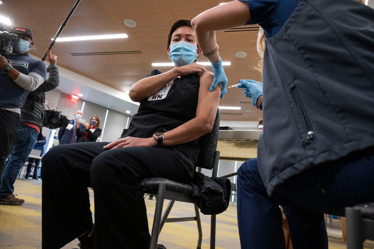 Eva Teniola, UC Davis Medical Center Emergency Department registered nurse, is the first person to be inoculated with the Pfizer-BioNTech COVID-19 vaccine by Heather Donaldson, a Registered Nurse with UC Davis Medical Center, Tuesday, Dec. 15, 2020 in Sacramento.