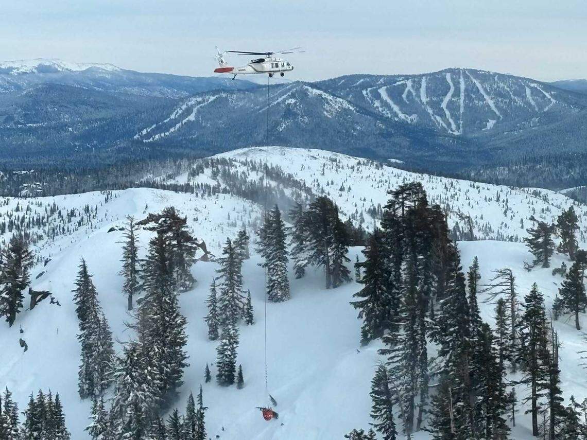 A PG&E helicopter drops water onto a snow-covered slope near Castle Peak on Saturday. The water drops were part of an avalanche mitigation effort conducted to reduce the risk of additional slides before search-and-rescue crews recovered victims of a deadly backcountry avalanche.