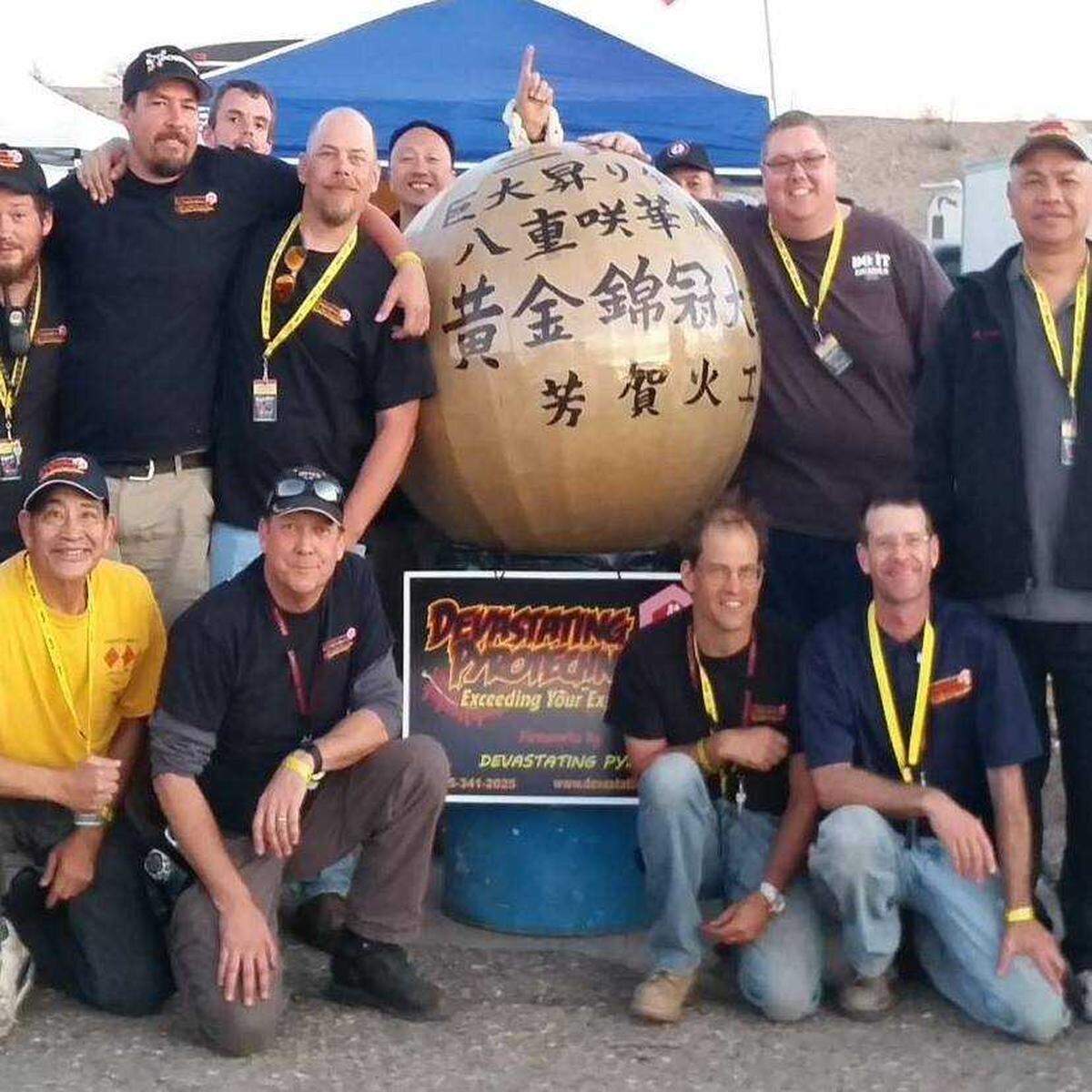 Craig Cutright, bottom row and second from left, is seen with others posing with a Devastating Pyrotechnics sign and oversized fireworks bulb in 2017 in a photo now deleted from Facebook.