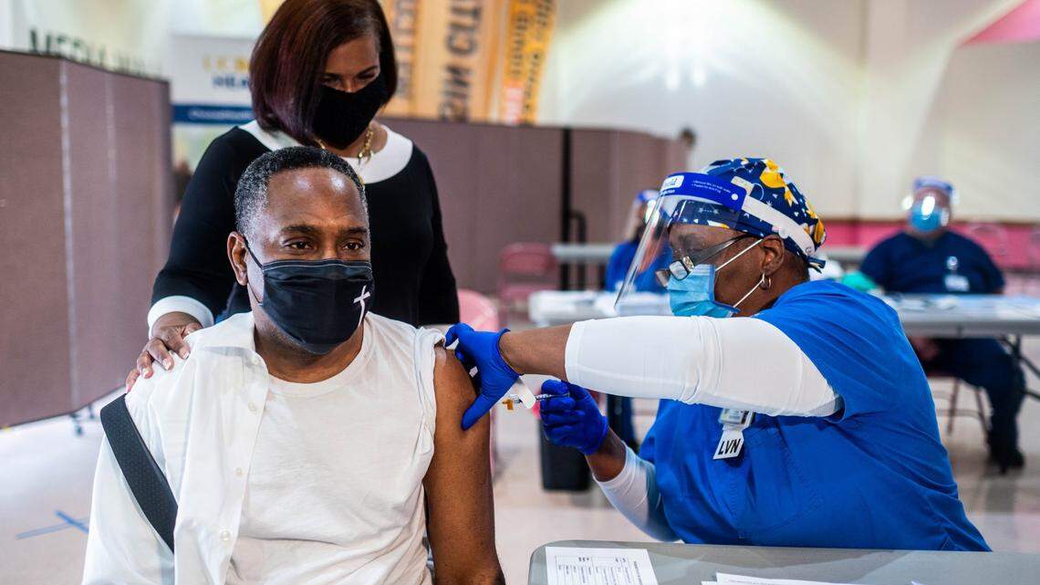 Senior Pastor Kenneth Reece gets a dose of the Moderna COVID-19 vaccine as his wife Lisa Reece stands by for comfort at St. Paul Missionary Baptist Church in Oak Park on Wednesday, March 31, 2021. “Hopefully this is the start of us getting back to normal,” he said. The weekly community COVID-19 vaccination clinic opened Wednesday at the church, in partnership with UC Davis Health, for residents who registered in advance. People age 50 and up in California become eligible for COVID-19 vaccines Thursday.