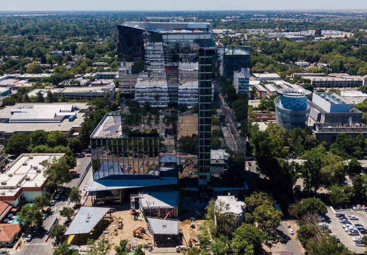 Downtown buildings reflect in the nearly completed facade of the new Natural Resources building in Sacramento on Tuesday, Aug. 4, 2020. The 21-story structure is between O and P streets east of 7th Street. At its base, on the right, stands the historic Heilbron House, an 1881 mansion that the state decided to preserve at its original location.