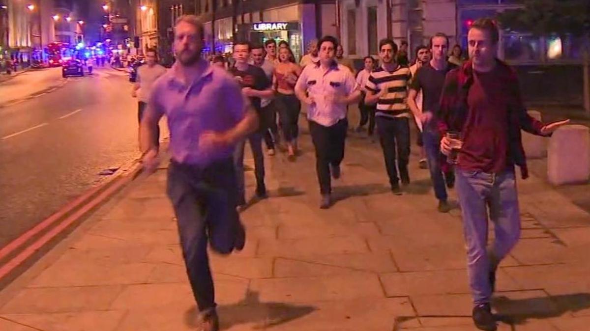 In this photo from video, people flee the London terror attacks. The man at front right holding his beer has been hailed by many as an example of British defiance and resilience. The four young men behind him are Folsom residents, from left, Jordan Stephen, 20, in the black and red shirt, Starry Faircourt, 19, in the bowling shirt, River Allen, 20, in the striped shirt, and Spencer Gilbert, 19, in the black shirt.