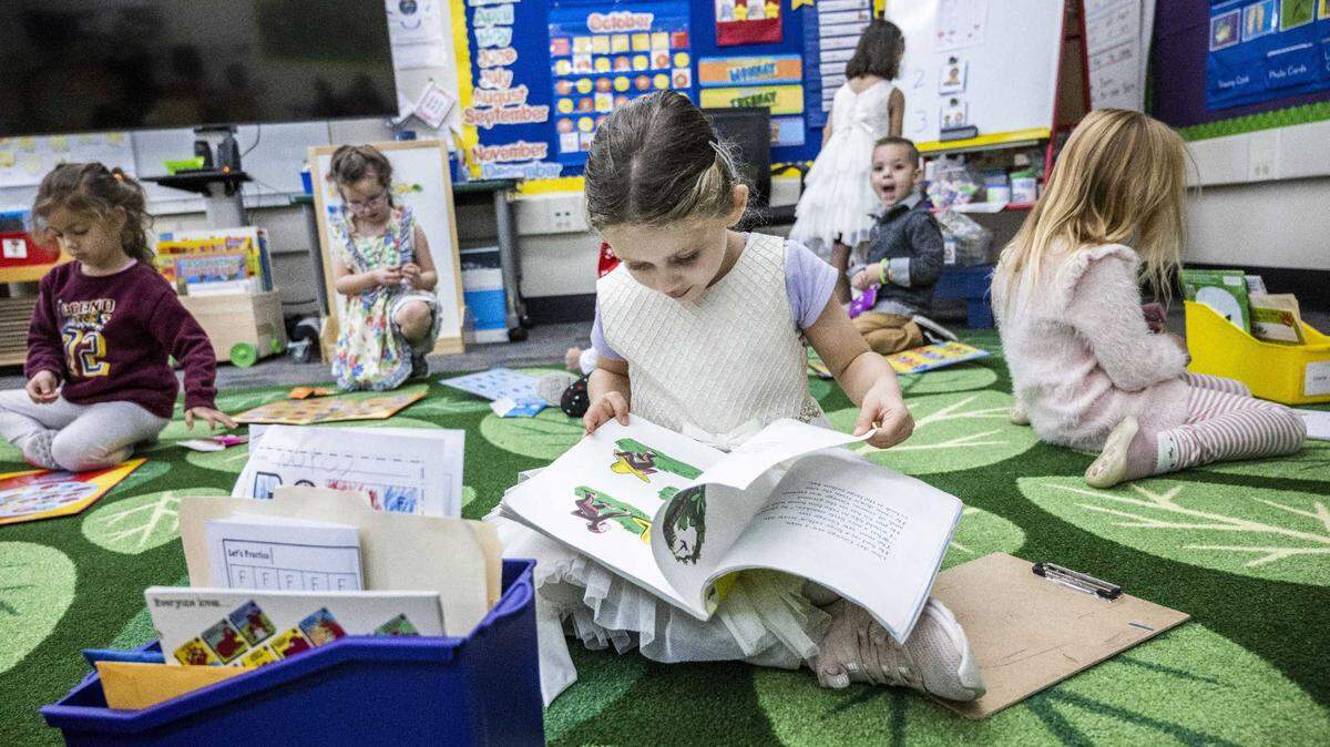 A transitional kindergarten student checks out a Curious George book in Sacramento in 2022. 