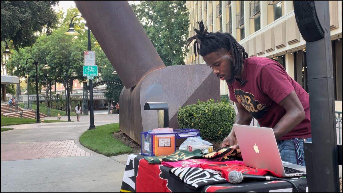 Kameron Lewis, also known as M’ster Lewis, setting up his table as he prepares to perform between Old Sacramento and Downtown Commons on Friday, Aug. 25.