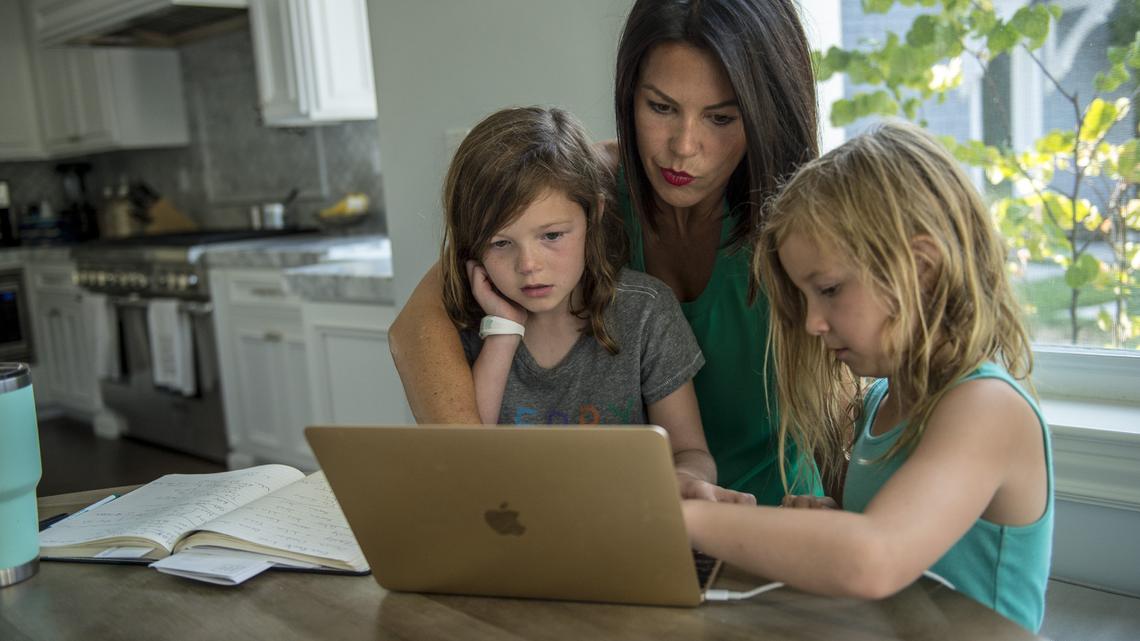Ashely Hutton works on her laptop as an independent contractor as her daughters Piper, 7, and Stella, 5, sit with her at the table, Thursday Aug. 2, 2018 at their home in Fair Oaks.