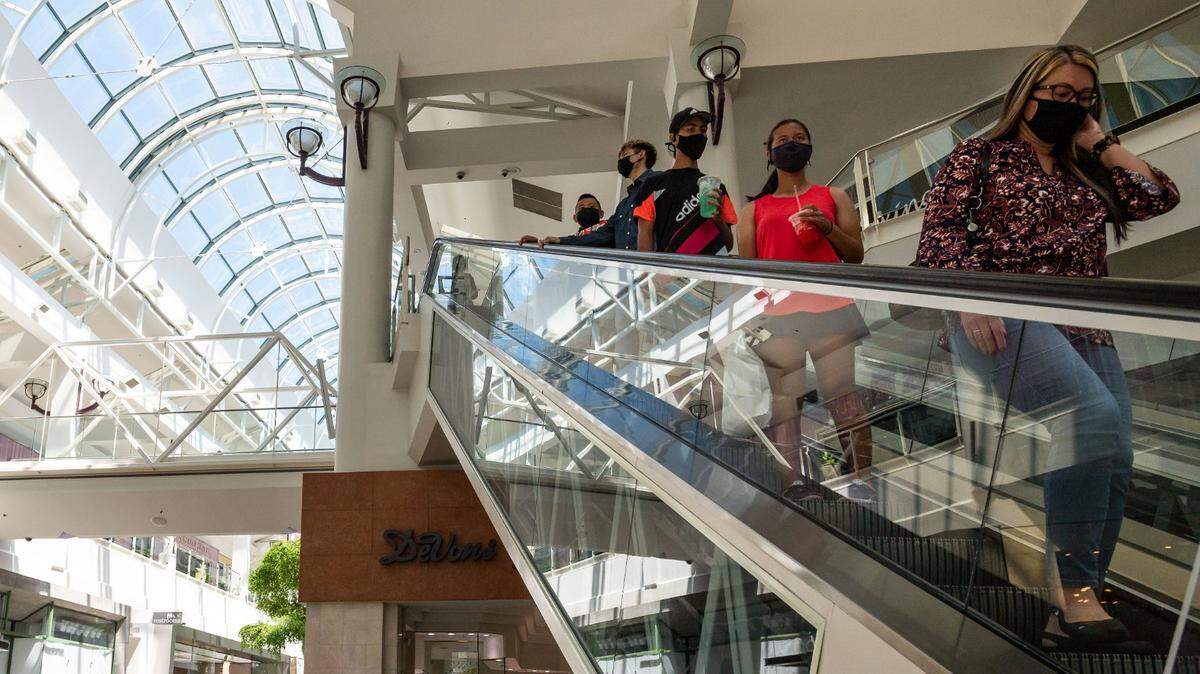 The Yen family, right, of Elk Grove, descends the escalator after picking up a gift at Arden Fair mall Tuesday, June 22, 2021, in Sacramento. Although theyve had their COVID-19 vaccinations, they said they generally plan to wear masks in public until they feel good taking them off.