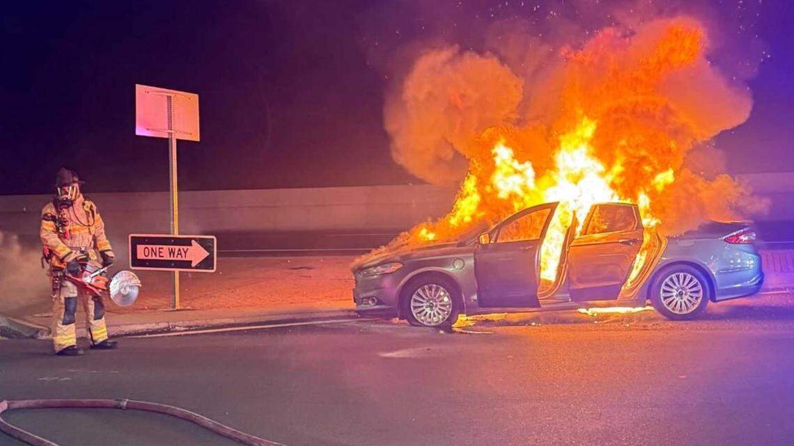 A firefighter stands next to a burning car on the Capital City Freeway near the Auburn Boulevard on-ramp in Arden Arcade on Monday, April 27, 2026. The vehicle caught fire after a California Highway Patrol pursuit of a juvenile driver who allegedly led officers on a high-speed chase.