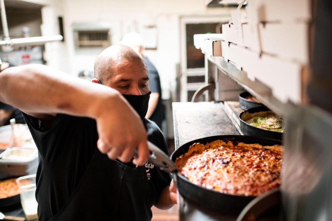 Zelda’s Original Gourmet Pizza employee Gerardo Diaz takes hot Chicago-style deep dish pizza pies out of the oven for takeout Tuesday, Dec. 22, 2020, in midtown Sacramento.