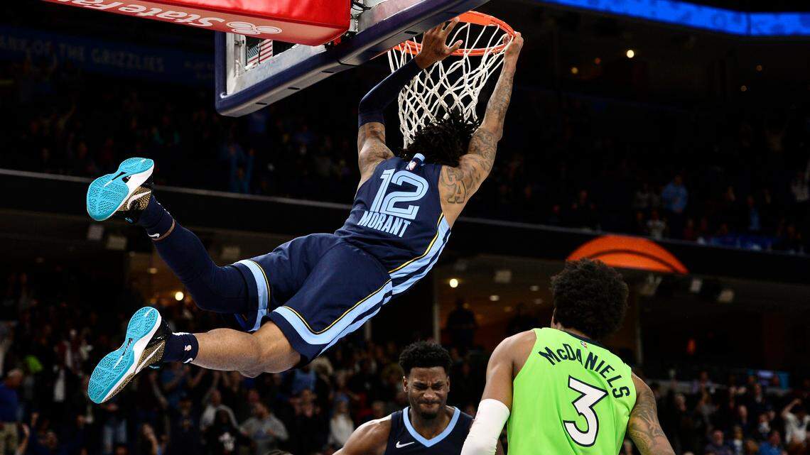 Memphis Grizzlies guard Ja Morant (12) hangs from the rim after dunking in the second half of an NBA basketball game against the Minnesota Timberwolves, Monday, Nov. 8, 2021, in Memphis, Tenn. (AP Photo/Brandon Dill)