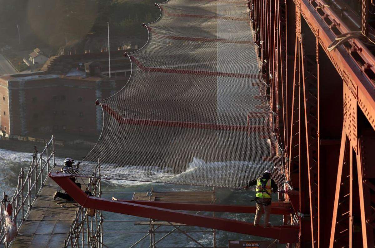 SAN FRANCISCO, CALIFORNIA - NOVEMBER 07: Workers make repairs to a new suicide prevention barrier on the Golden Gate Bridge on November 07, 2023 in San Francisco, California. A suicide prevention barrier made of a net of stainless steel cables on the Golden Gate Bridge is nearing completion after 6 years. The project originally projected to cost $76 million has ballooned to over $215 million and is expected to be finished by the end of the year. An estimated 30 to 40 people jumped from the bridge each year prior to the construction of the netting compared to 6 so far this year. Since the Golden Gate Bridge was built in 1937, an estimated 2,000 people have jumped to their deaths from the span. (Photo by Justin Sullivan/Getty Images)