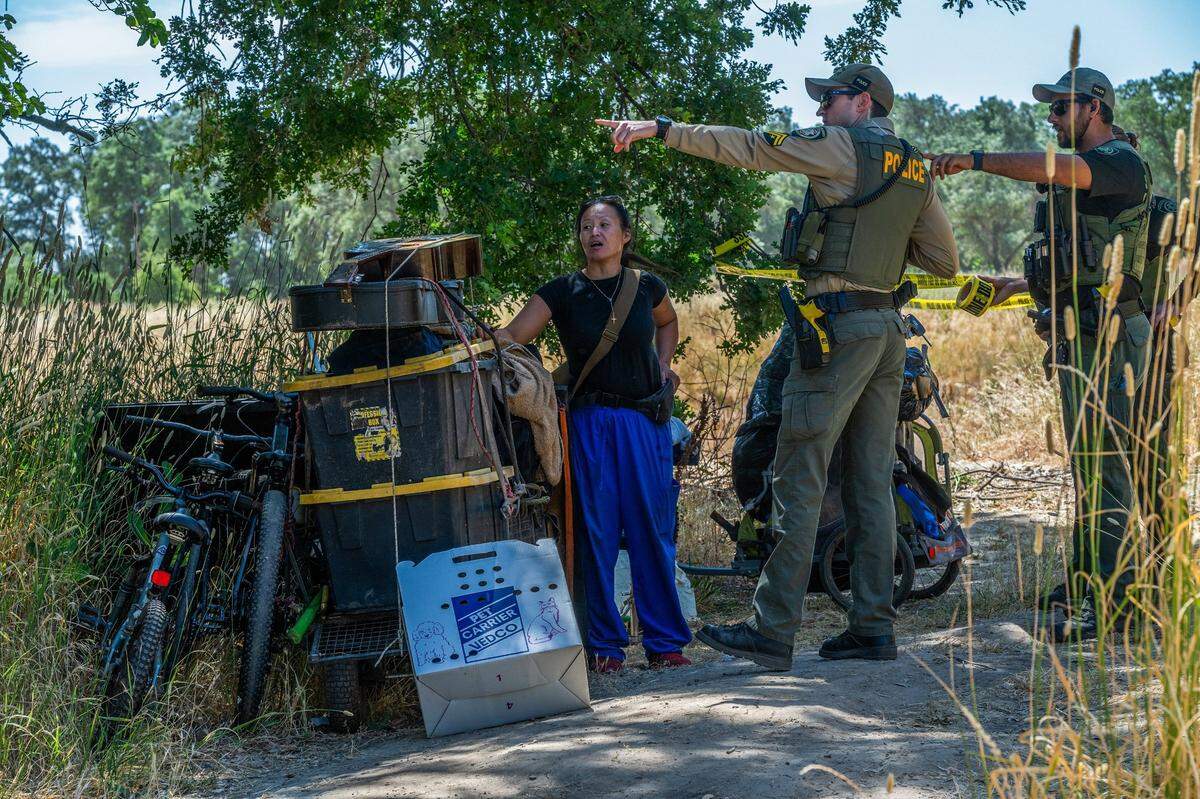 Chaming Vang, 38, is given directions about where to move her belongings as Sacramento County Park Rangers tape off access back to her homeless encampment structure during a sweep in Rio Linda on Monday, June 17, 2024.
