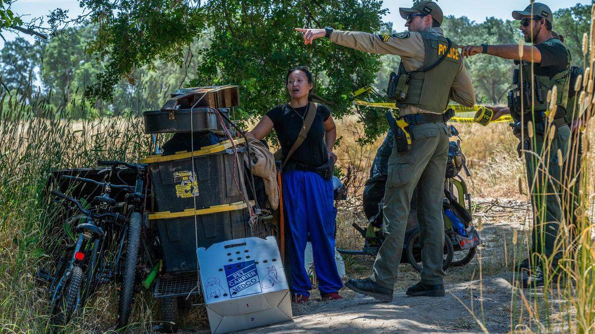 Chaming Vang, 38, is given directions about where to move her belongings as Sacramento County Park Rangers tape off access back to her homeless encampment structure during a sweep in Rio Linda on Monday, June 17, 2024.