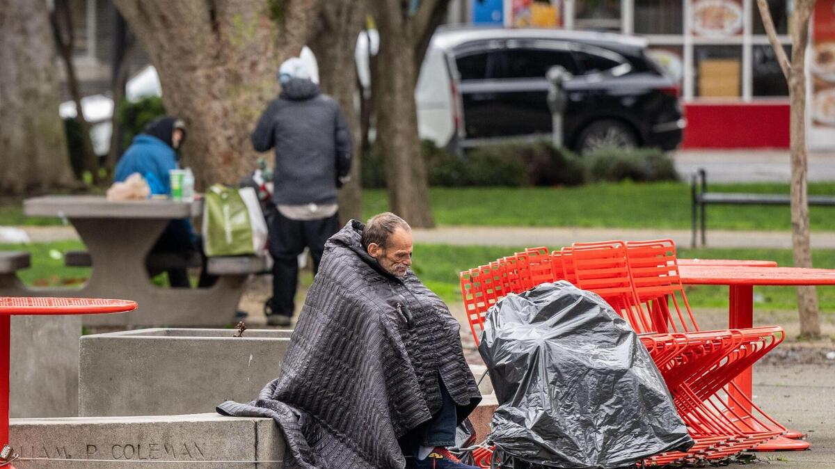 A man rests at Cesar Chavez Plaza on Thursday, Feb. 8, 2024. Signs posted Wednesday state that a movie will be filmed in the area for three days starting Saturday.