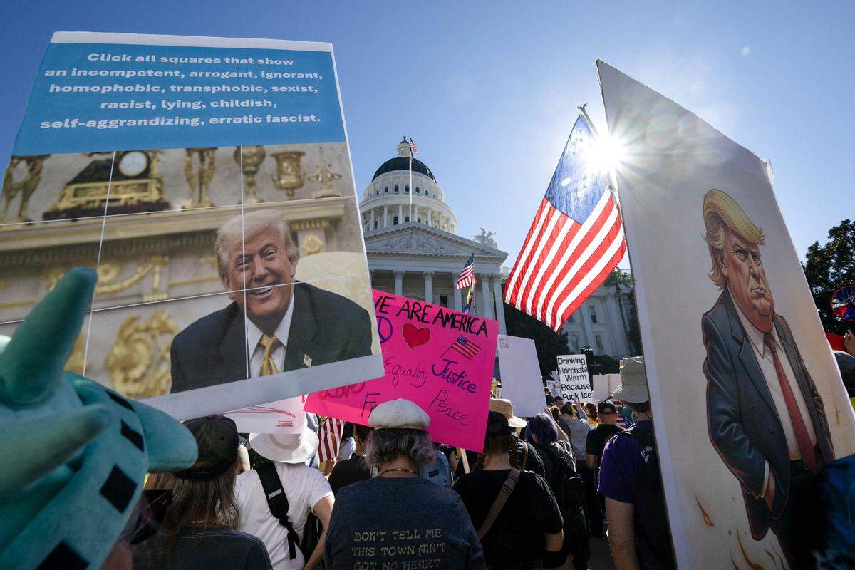Demonstrators hold signs during the "No Kings" protest at the state Capitol in Sacramento on Saturday, Oct. 18, 2025.