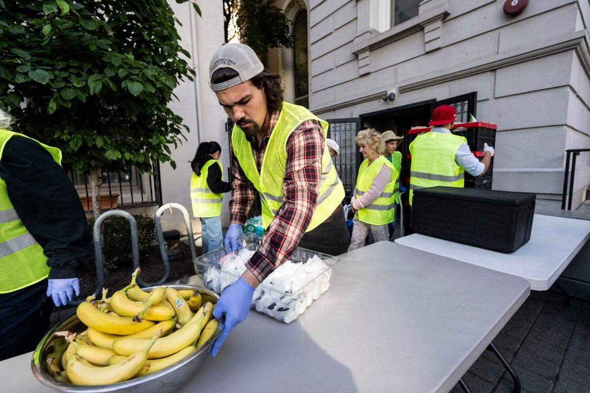 Chuck Tollner, a volunteer at the Brown Bag Lunch program at the Cathedral of the Blessed Sacrament, places food on a table for homeless people on Thursday.