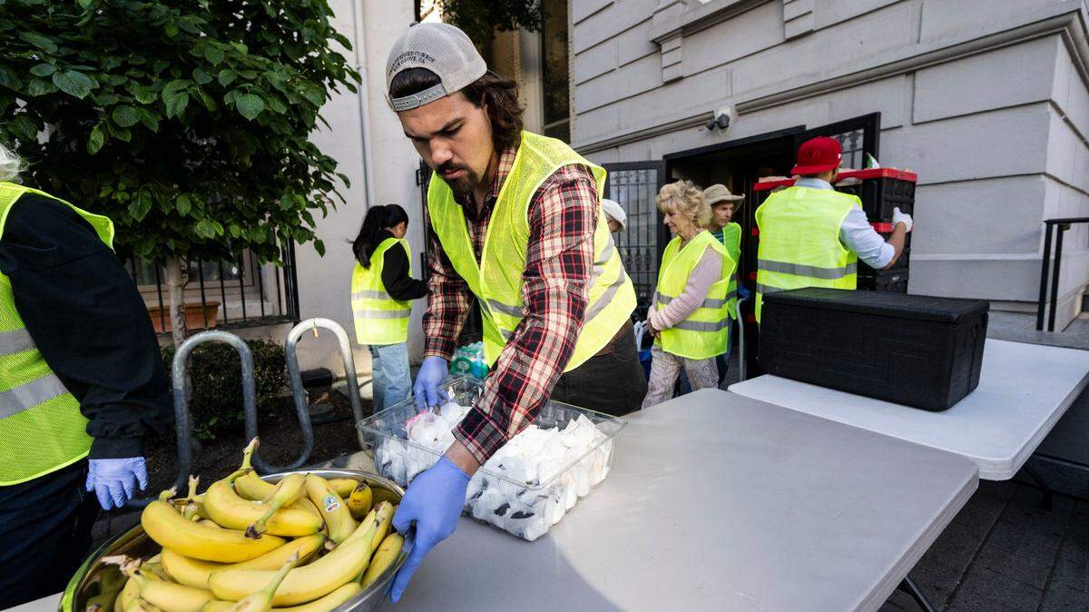 A volunteer at the Brown Bag Lunch program at the Cathedral of the Blessed Sacrament in downtown Sacramento places food on a table for homeless people in June. 