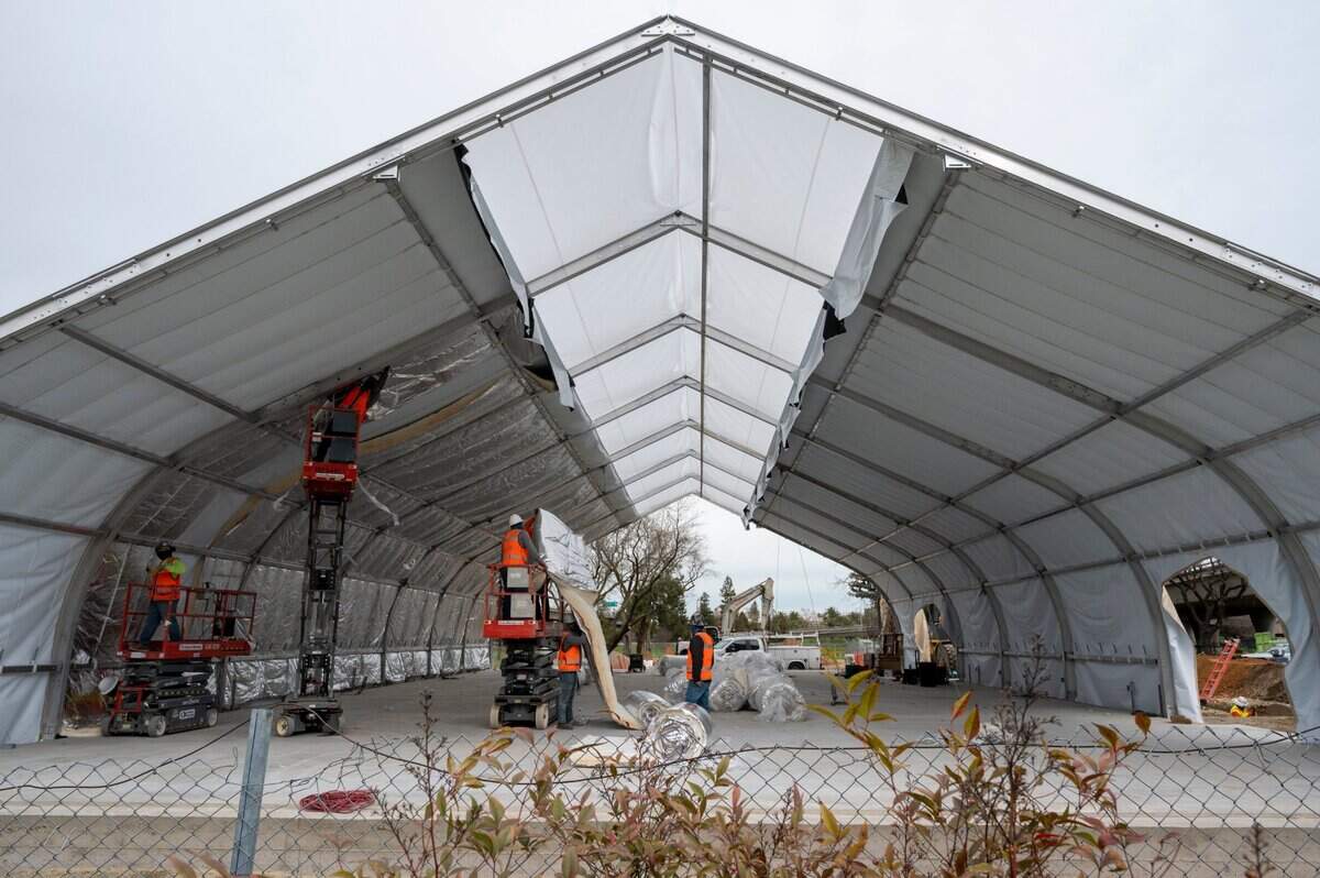 Installation of a city-run Sprung shelter for the homeless is underway Thursday, Feb. 11, 2021, on a lot owned by Caltrans next to the W-X freeway off of Broadway near Alhambra Boulevard near the edge of Oak Park and Curtis Park.