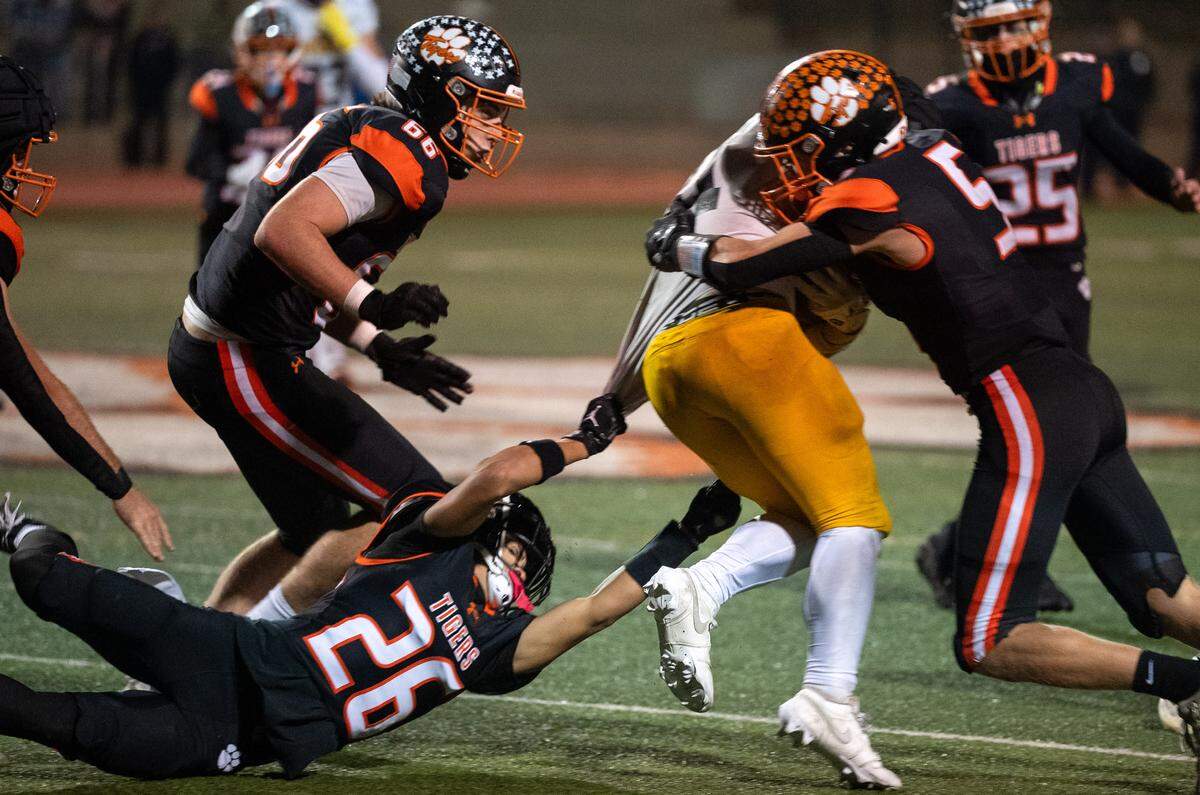 Roseville Tigers linebacker Jack Walker (5) and wide receiver Ben Jordan (26) tackle Hughson Huskies running back Eli Wilbanks (21) for a short gain in the second half of a CIF Sac-Joaquin Section Division IV semifinal in Roseville on Friday, Nov. 21, 2025. The Tigers recovered the fumble. 
