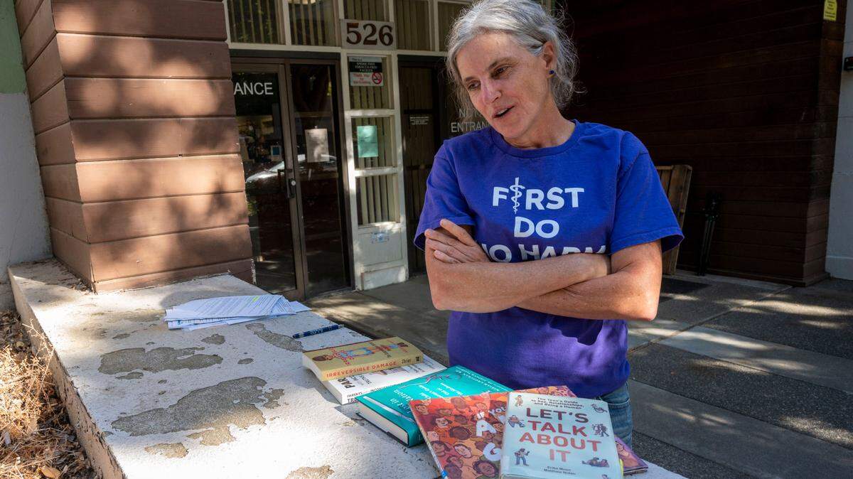Yolo County Moms for Liberty chapter chair Beth Bourne stands outside a closed-door meeting at the Davis Joint Unified School District offices Sept. 26 as board members met behind closed doors with police over a series of bomb threats to Davis schools. She shows books from the Davis Library she felt were inappropriate for children.