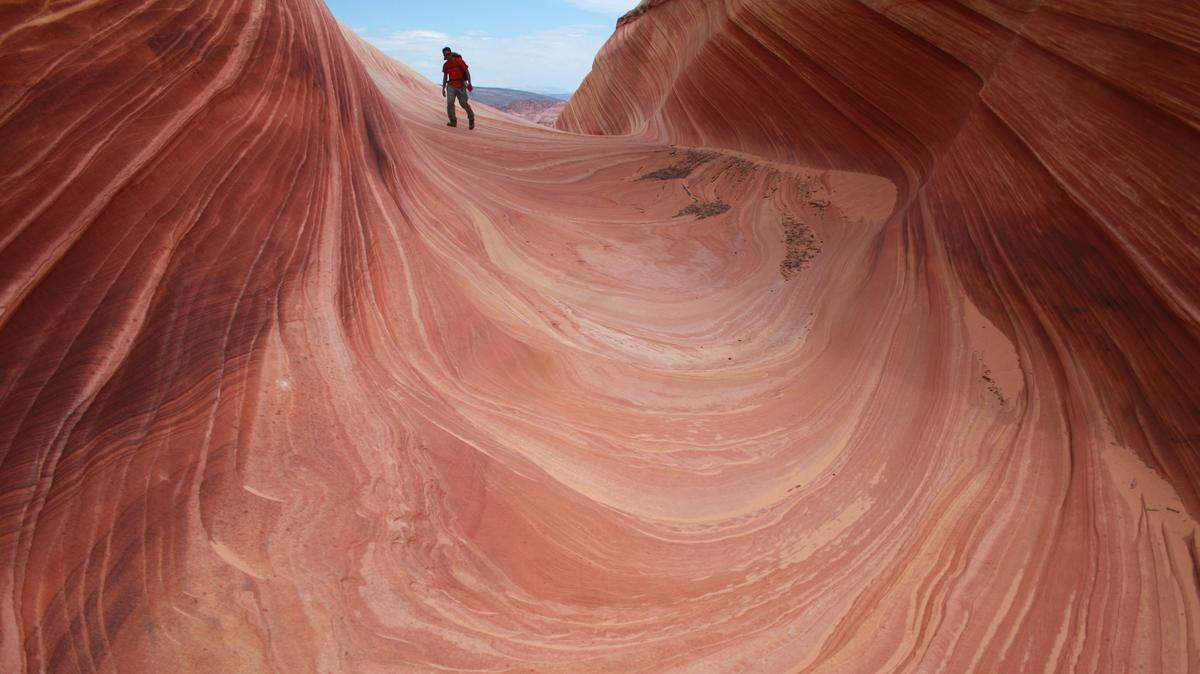 A hiker walks on a rock formation known as The Wave in the Vermilion Cliffs National Monument in Arizona in 2013. A 49-year-old Belgium man has died in an apparent heat-related death while hiking a popular spot near the Utah-Arizona border called “The Wave.”