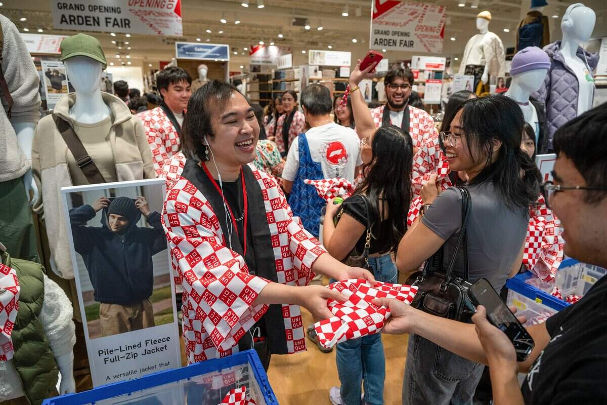 Uniqlo employee Darrian Phienemanh, center, hand a gift bag to a customer during the store’s grand opening at Arden Fair mall in Sacramento on Friday, Sept. 13, 2024. Hundreds lined up in the mall to attend the festivities, which included a traditional Japanese taiko drum performance and ribbon cutting. The store opening is part of Uniqlo’s growth in North America, which includes over 20 new locations planned for 2024.