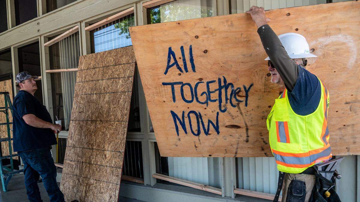 Frank Brown, right, with JH Bryant Jr. Inc. carries a piece of plywood to board up windows at the Bank of America at Alhambra Boulevard and K Street in Sacramento on Monday, April 19, 2021. The work was being done in anticipation of potential unrest after a verdict in the trial of Derek Chauvin, the former Minneapolis police officer charged with murdering George Floyd.