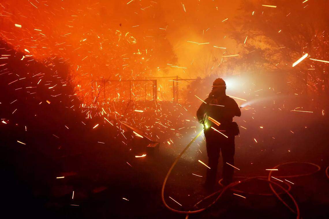 Firefighters battle the Franklin Fire on Dec. 10, 2024, next to a business along Pacific Coast Highway in Malibu.
