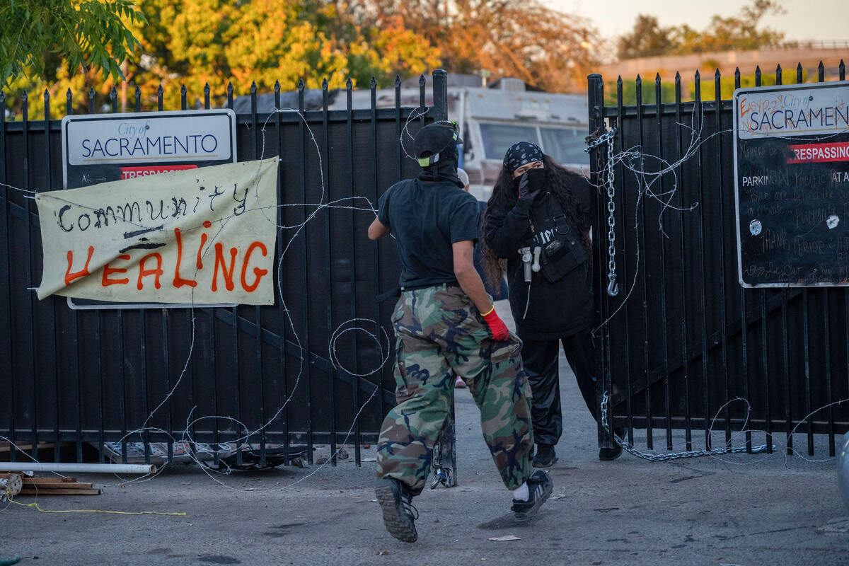 Camp Resolution residents place barbed wire on the gate of the homeless encampment Monday with the hope of warding off city of Sacramento crews charged with removing camp residents.