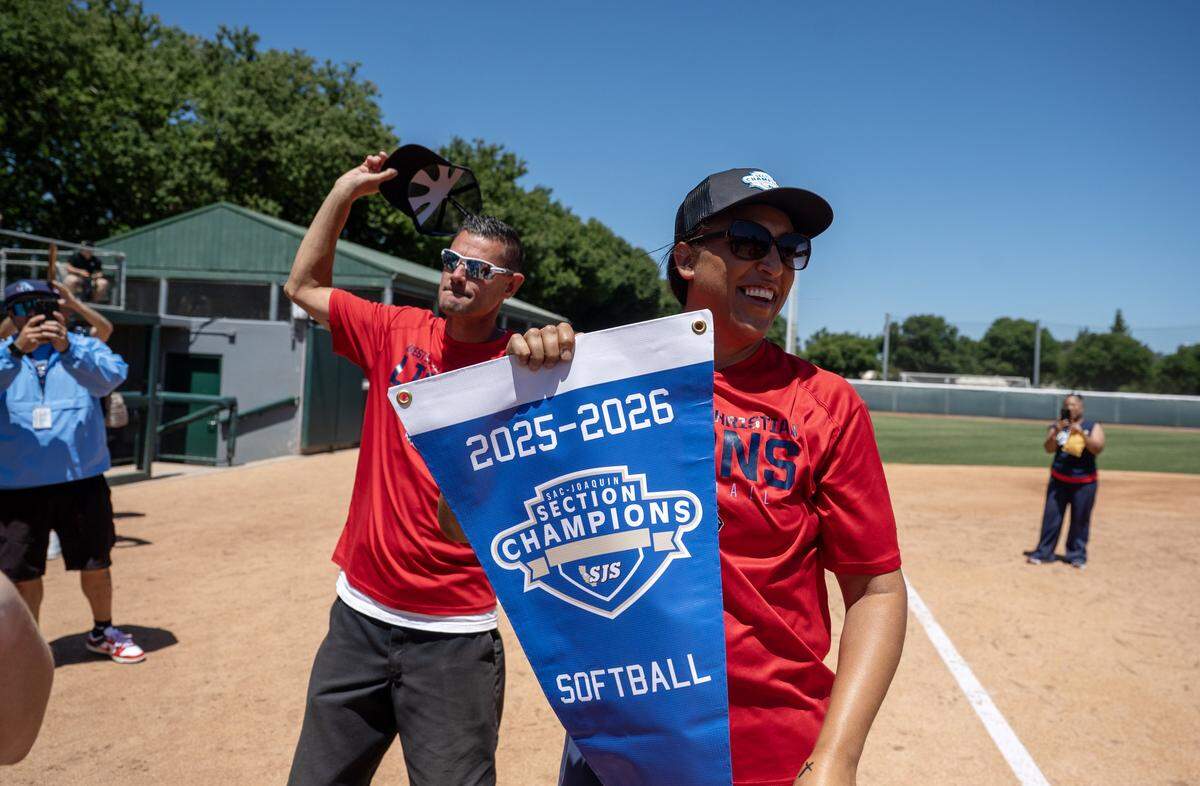 Destiny Christian Academy Lions coach Shannon Tuua holds the championship banner following the 4-1 victory over the Vanden Vikings on Saturday in the CIF Sac-Joaquin Section Division III softball championship at Sacramento State.