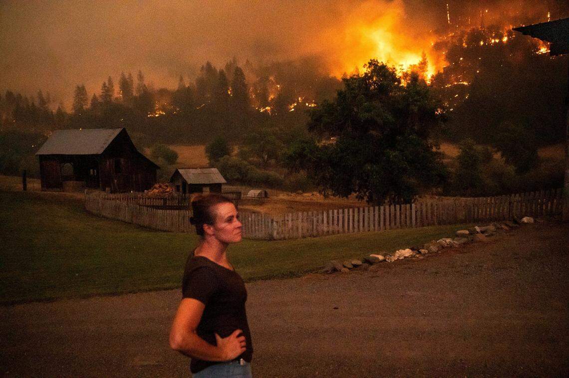 Angela Crawford watches as a wildfire called the McKinney fire burns a hillside above her home in Klamath National Forest, Calif., on Saturday, July 30, 2022. Crawford and her husband stayed, as other residents evacuated, to defend their home from the fire.