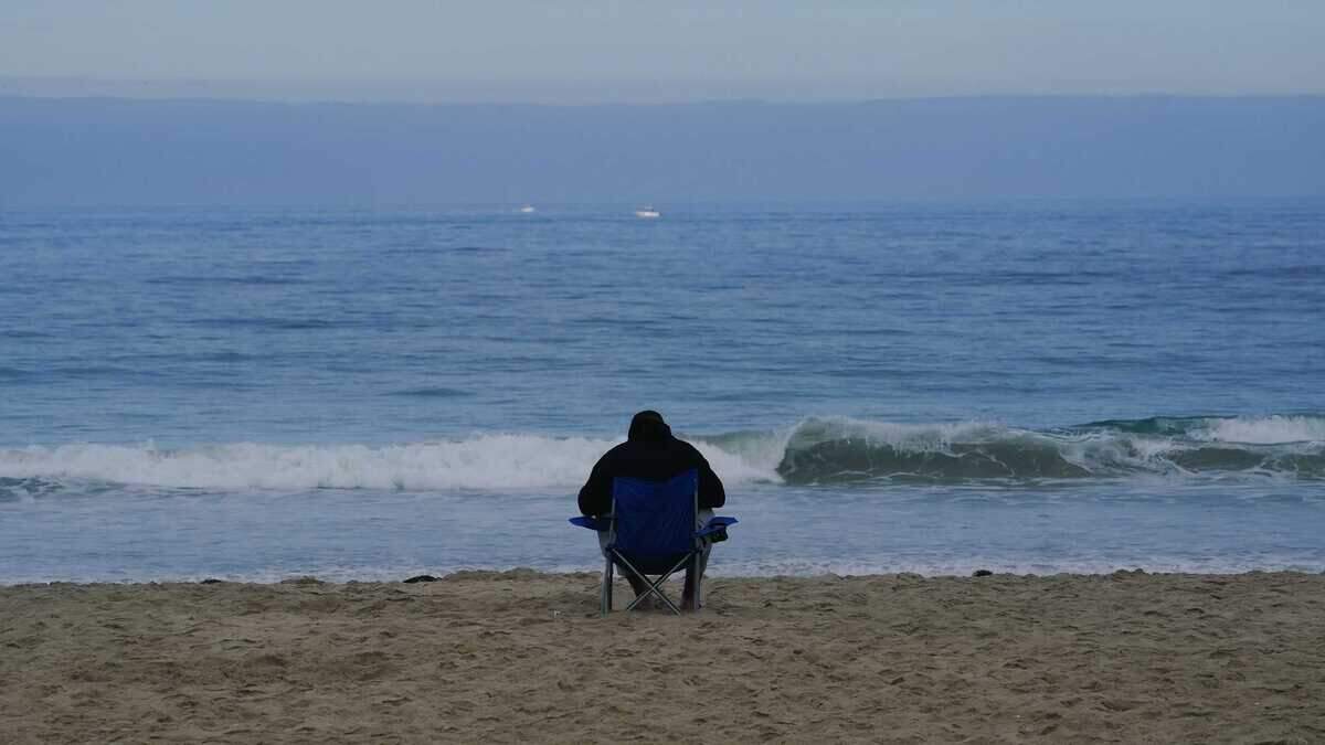 In Mission Beach on Saturday, a lone beachgoer sits in the calm of the approaching hurricane. Forecasters say Hurricane Hilary could produce âpotentially catastrophicâ flooding across San Diego County this weekend.