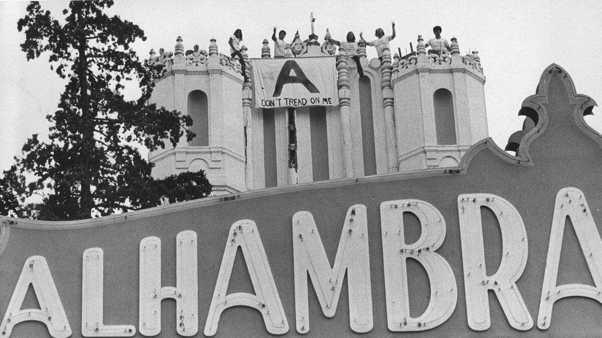 Save the Alhambra boosters with a “battle flag” that says “Don’t tread on me” wave from atop the old theater building in January 1973, before the East Sacramento structure’s demolition.