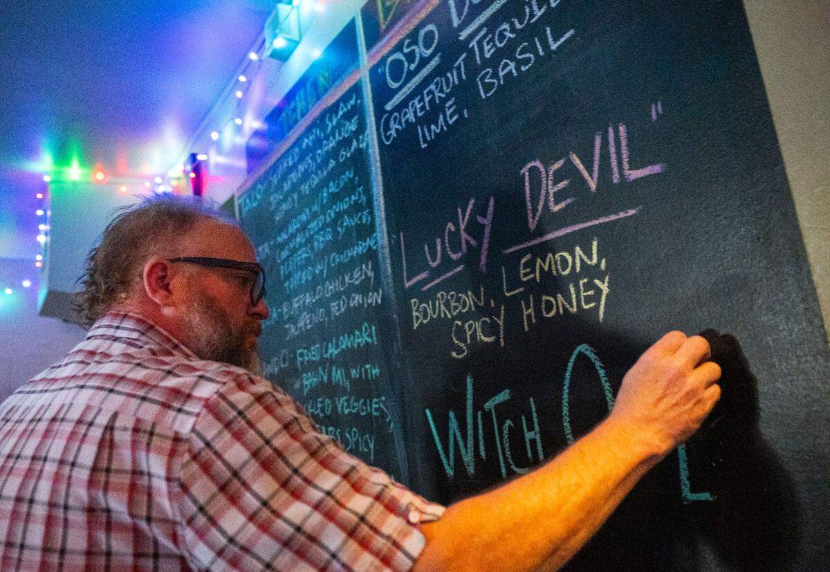 Josh Milholm, co-owner of the Golden Bear in midtown, writes out cocktail specials on Saturday. His business supports a proposal the Sacramento City Council will consider that would allow bars and restaurants to sell open containers of alcohol for patrons to take out onto streets during designated events.