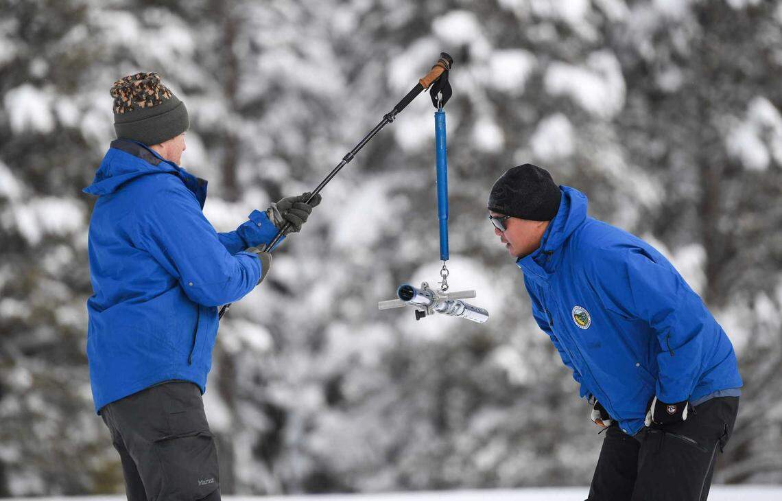 Anthony Burdock, left, an engineer for the state Department of Water Resources, holds up a snowpack instrument for Sean de Guzman during the first snowpack measurement Tuesday at Phillips Station. The state’s snowpack measured 174% of the average depth for Jan. 3 and was more than 60% of the April 1 average.