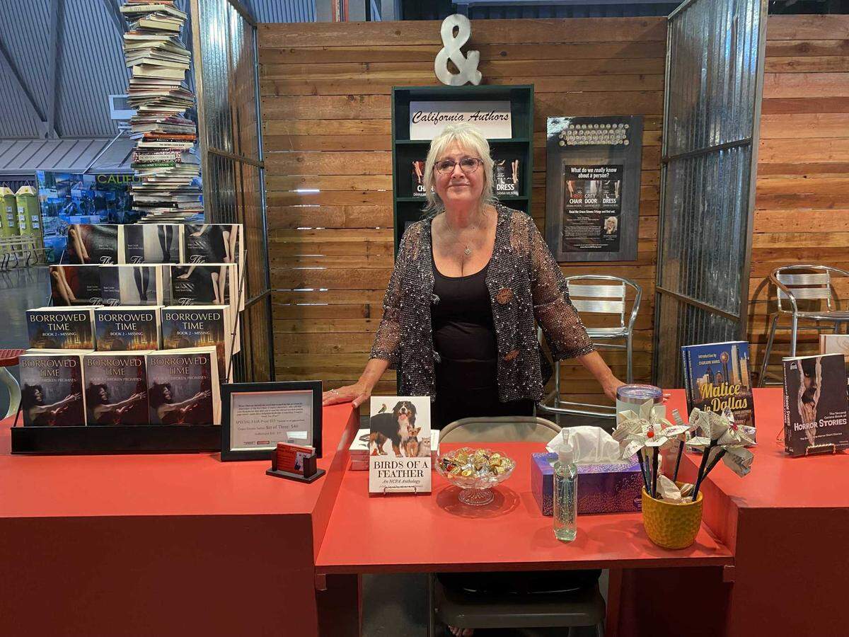 Danna Wilberg posing with her books at the California State Fair Authors Booth.