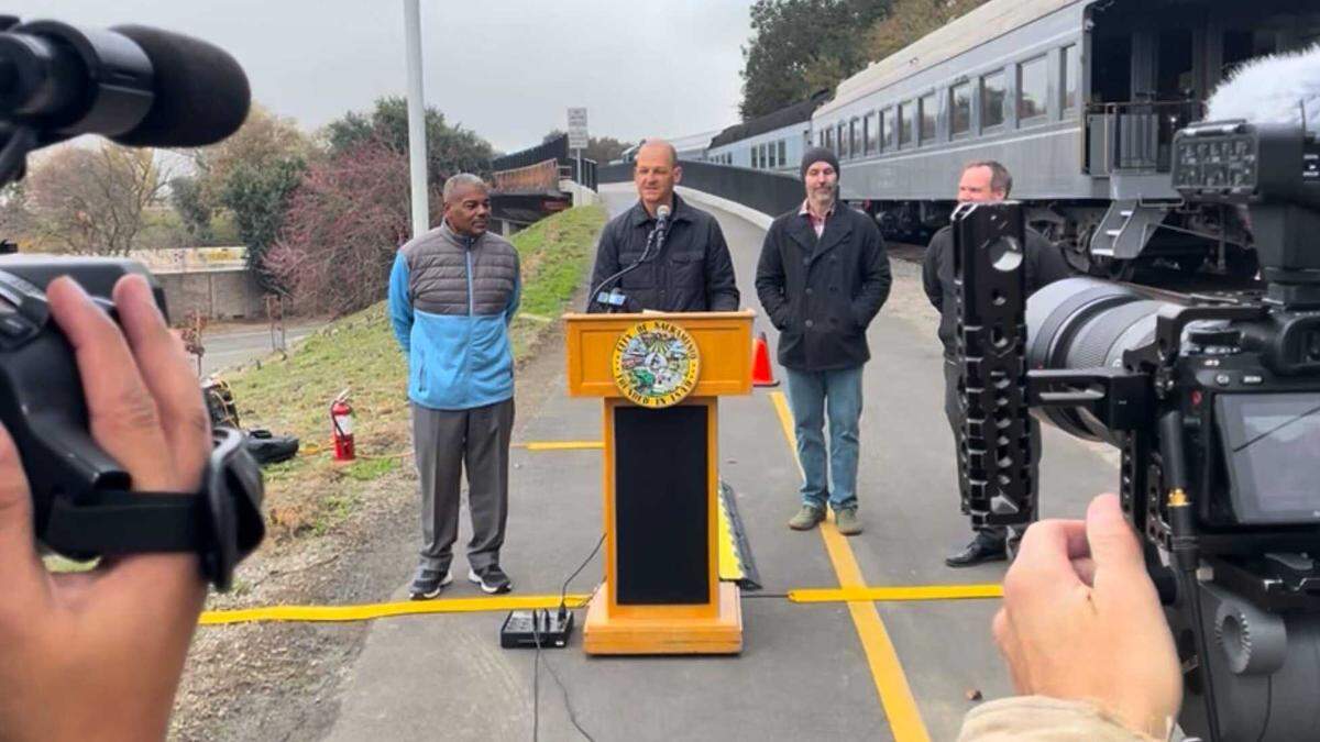 Sacramento Mayor Kevin McCarty speaks from the podium beside City Councilmember Rick Jennings, left, during a ceremony to reopen the Del Rio Trail bridge over Interstate 5 on Tuesday, Dec. 16, 2025, in Sacramento. 
