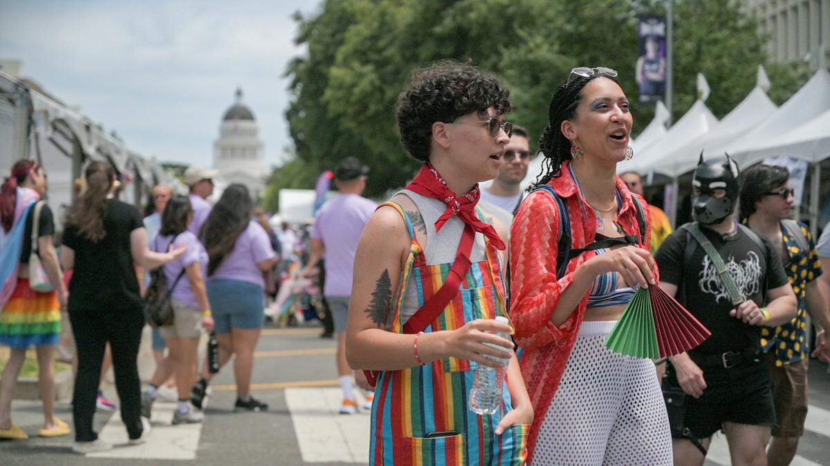 Mona Dehaesus, center, and Taylor Longmire, right, explore the Sacramento Pride Festival on Capitol Mall on Saturday, June 8, 2024.