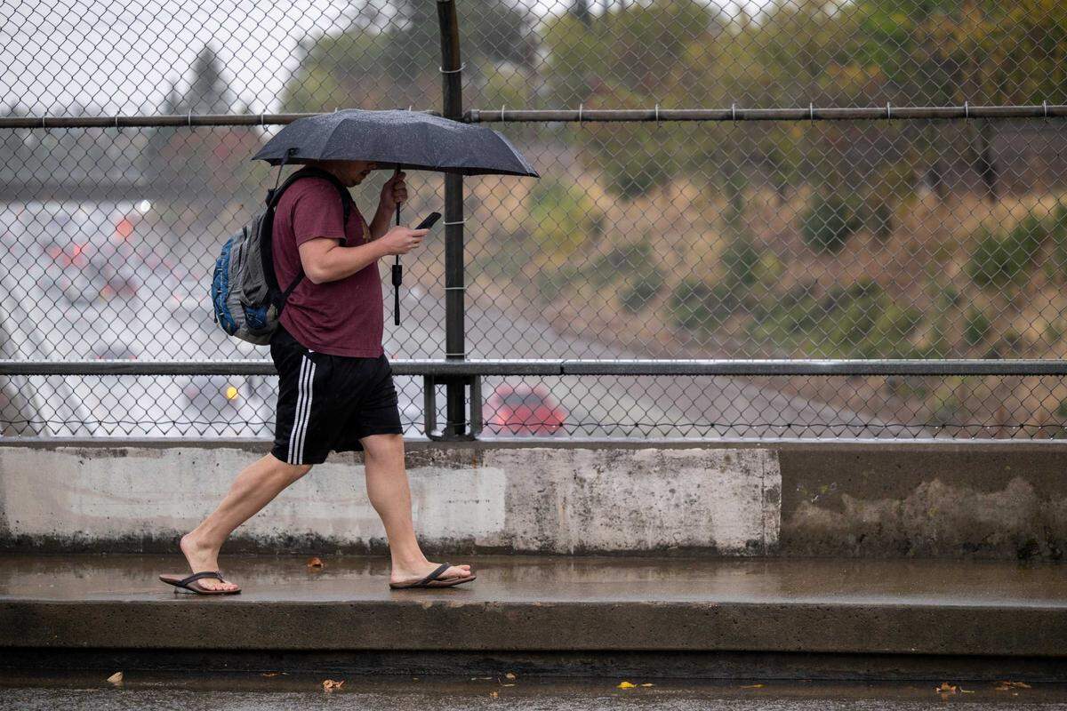 A pedestrian walks in the rain on 48th Street over Highway 50 in Sacramento in 2022. California drivers strike and kill about 1,000 people walking each year, and many of those crashes are considered preventable with infrastructure changes.