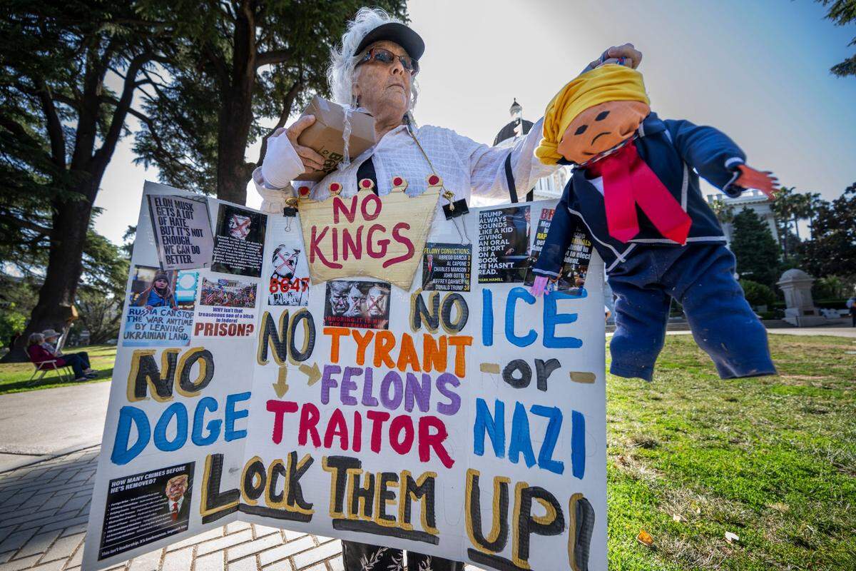 Sacramento resident Debi Earl holds a sign and a doll dressed like President Donald Trump during the “No Kings” protest at the state Capitol on Saturday, June 14, 2025. 