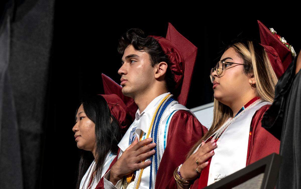 Student body president Fancy Thao, left, valedictorian Abdul Majidnushin, center, and senior class president Mariah Vasquez stand for the national anthem at the Hiram Johnson High School graduation on June 11, 2025.