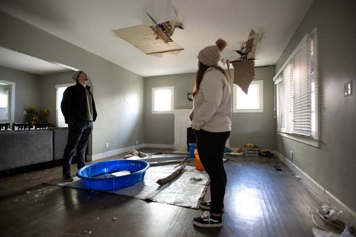 Hunter Parnell and Molly O’Keefe look at damage to their living room from a fallen tree at their home Wednesday in the Curtis Park neighborhood of Sacramento. They were still waiting for an insurance adjuster to assess the damage to their home.