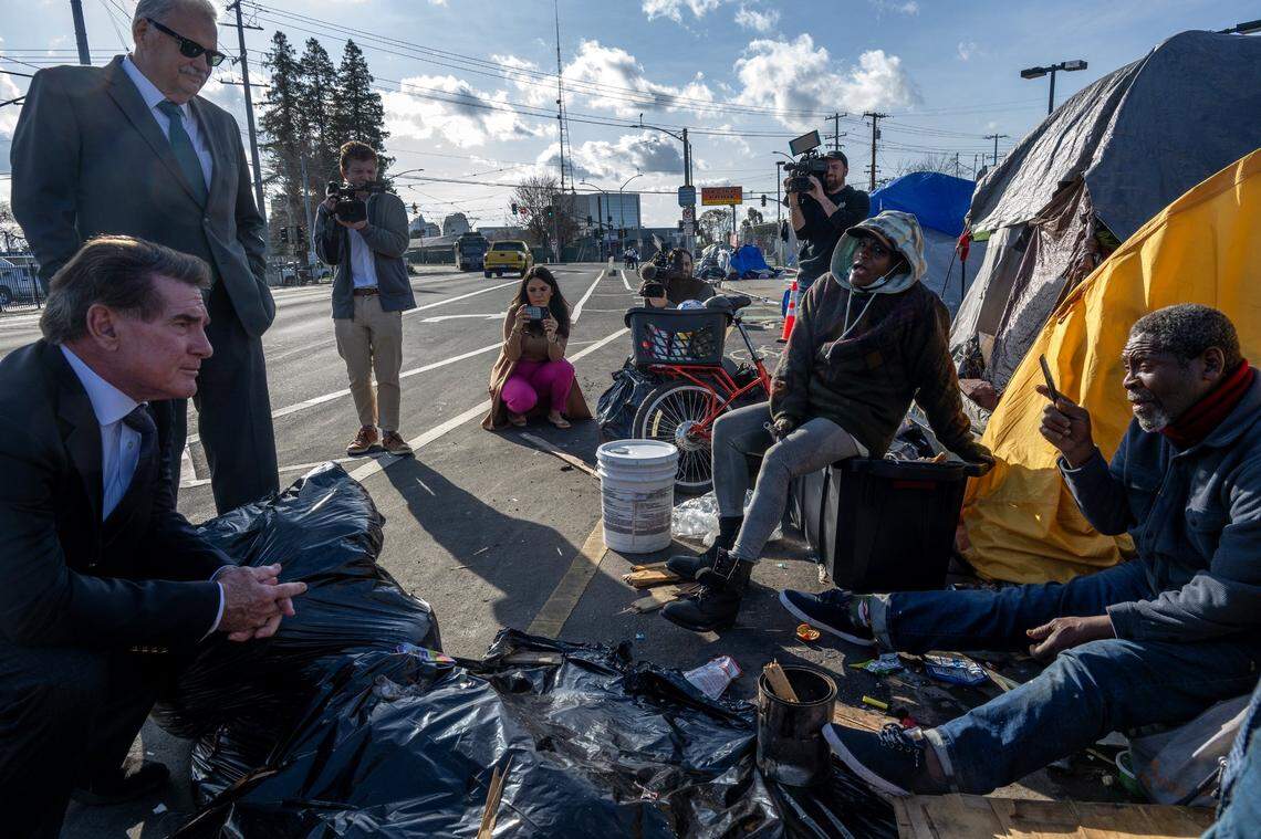 Baseball legend Steve Garvey, left, and former Sacramento Sheriff John McGinness, behind him, speak with Lavell Wright, 66, right, as they tour a homeless encampment in Sacramento on Wednesday.