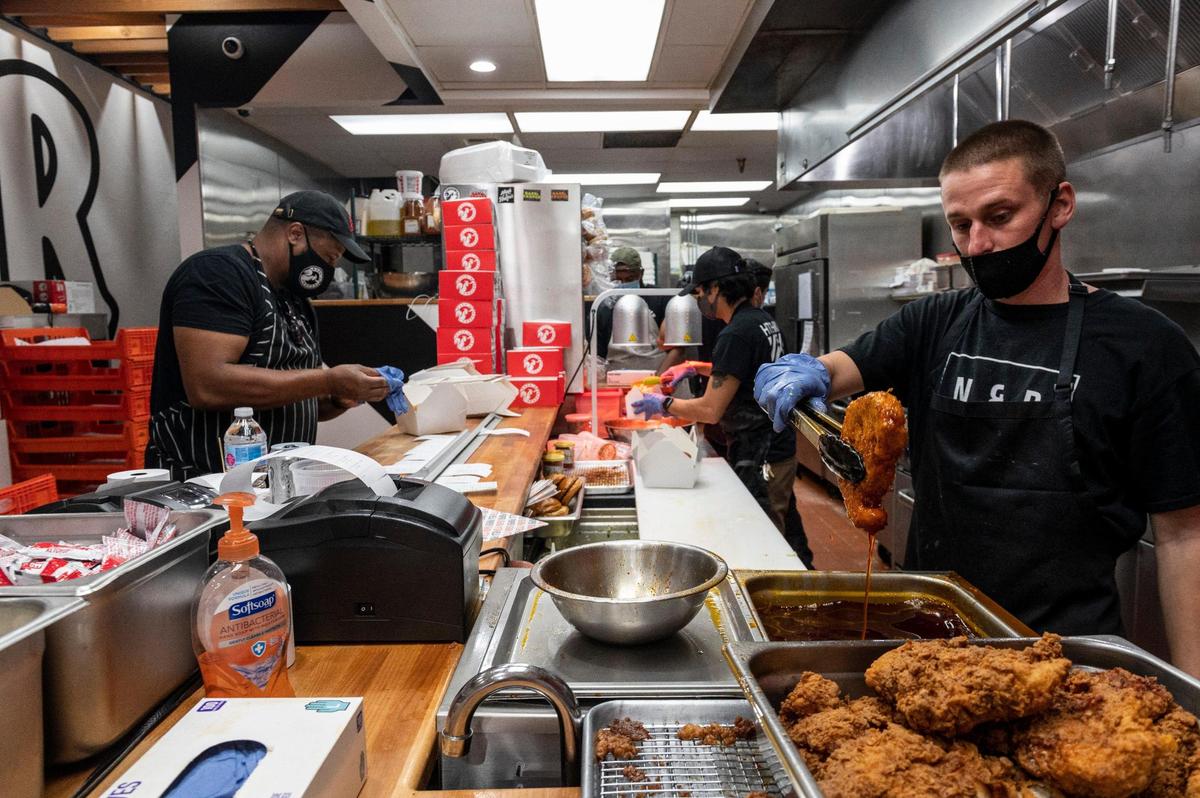 Owner Cecil Rhodes, left, works on orders while Matt Rocha, right, lifts a chicken thigh out of hot oil and Gavin Okamoto, center, makes sandwiches at Nash and Proper’s new takeout restaurant on K Street in downtown Sacramento on Thursday, Sept. 24, 2020.