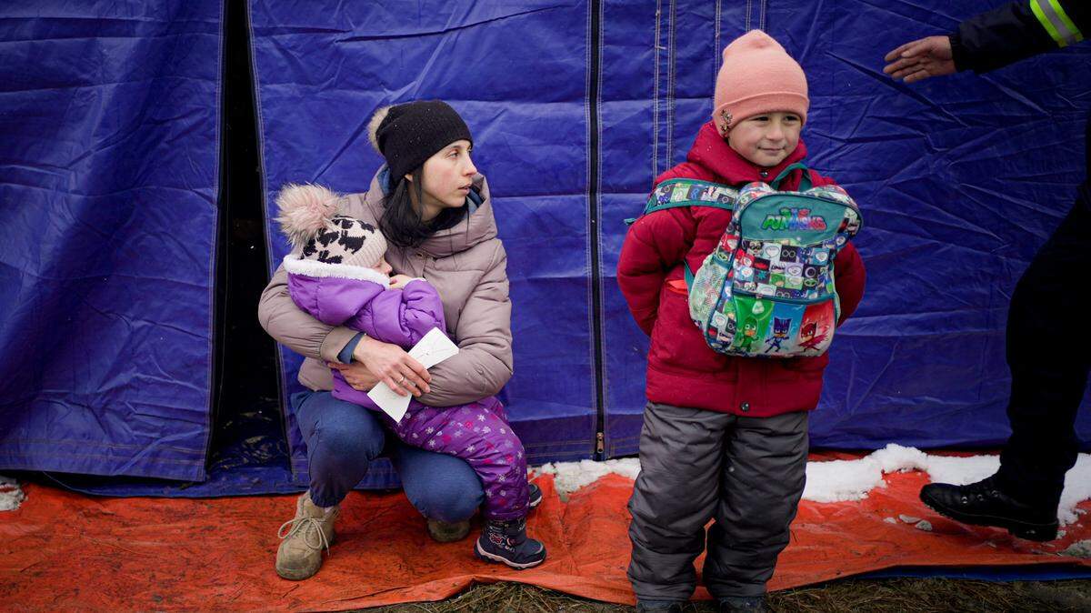 Sasha Moskalu, 33, from Bukovyna region of Ukraine, holds her 2-year-old daughter Sofia near her 6-year-old son Danic as they take shelter near a tent shortly after crossing into Romania fleeing the conflict from neighboring Ukraine, in Siret, Romania, Wednesday, March 2, 2022. The U.N. refugee agency says more than 874,000 people have fled Ukraine since Russia’s invasion last week and the figure is “rising exponentially,” putting it on track to cross the 1 million mark possibly within hours. (AP Photo/Renata Brito)